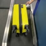 Mala amarela na esteira no balcão de despacho de bagagem e a telinha com o peso da mala.
